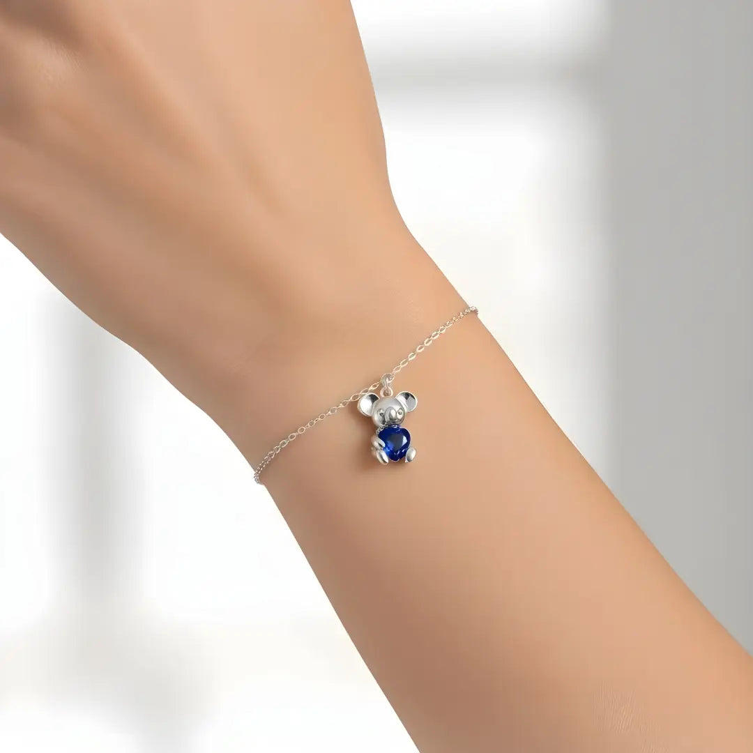 Silver bracelet with a Koala sapphire heart shape charm on a person's wrist against a white background