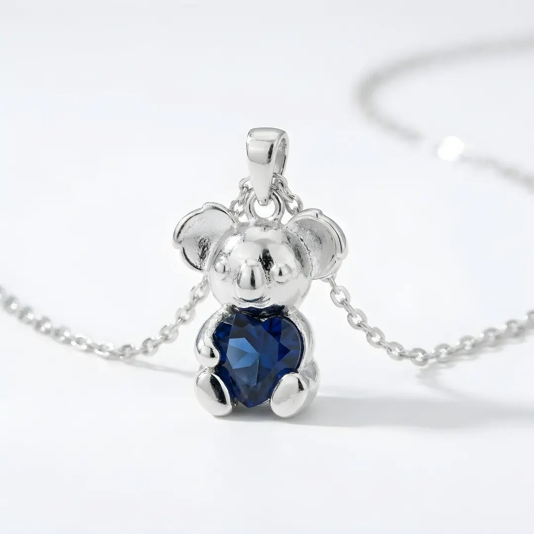 Silver Koala pendant with a sapphire cz heart on a white background