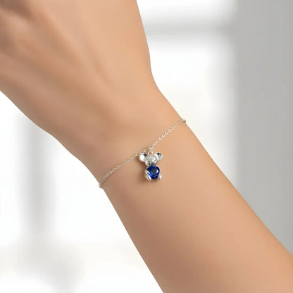Silver bracelet with a Koala sapphire heart shape charm on a person's wrist against a white background