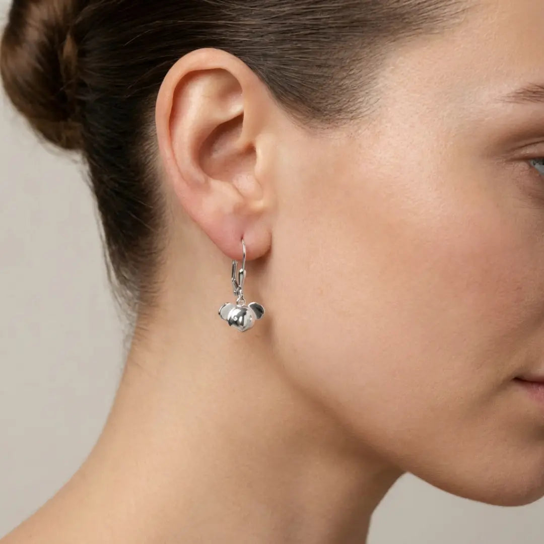 Close-up of a woman wearing a silver earring with a small a Koala head.