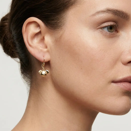 Close-up of a woman wearing 9ct gold earrings with a neutral background
