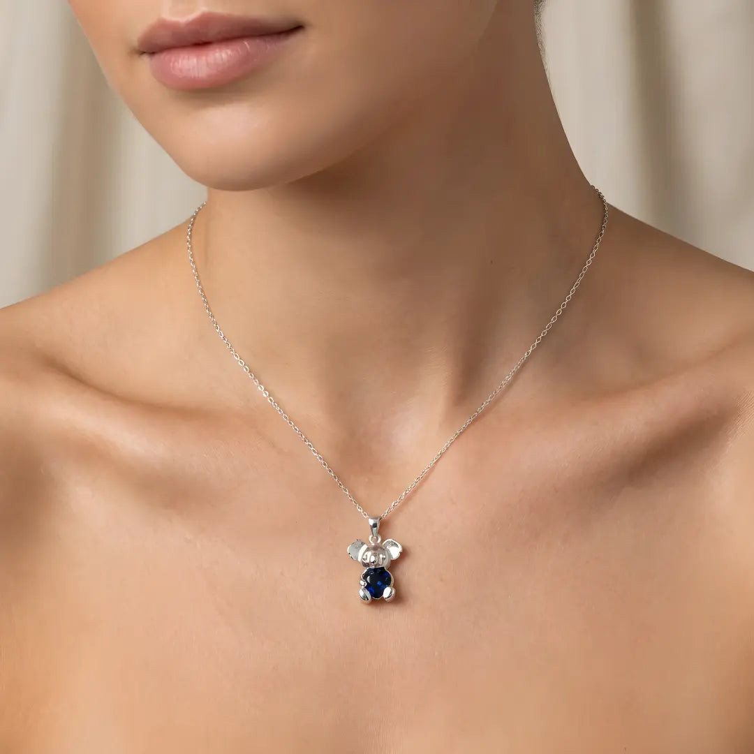 Silver necklace with a Koala pendant with sapphire heart cz on a model against a neutral background